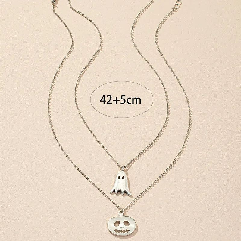 Two silver alloy pendant necklaces: one cartoon pumpkin and one cartoon ghost on a light background