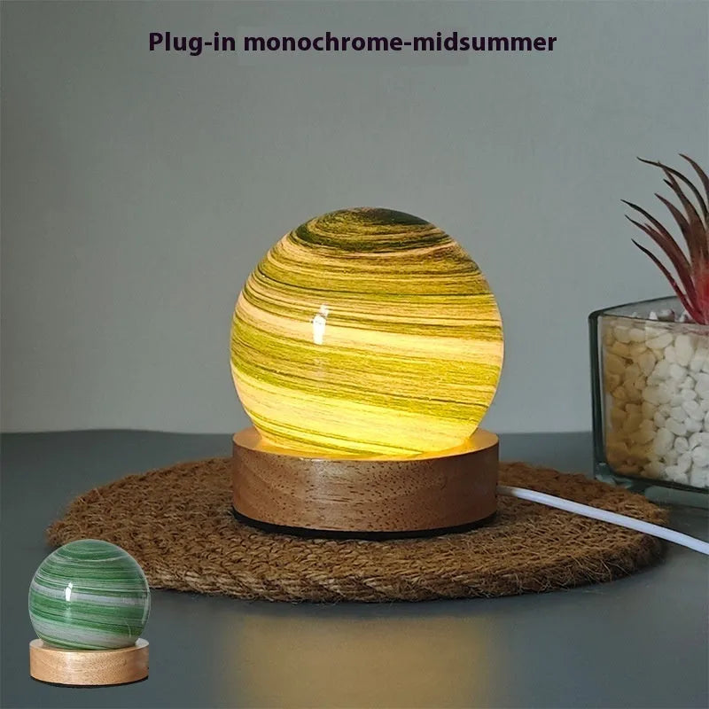 Modern planet-shaped USB night light with dimming on a desk.