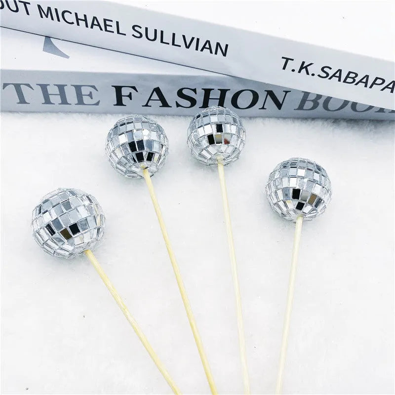 Small glass mirrored disco ball cake decoration attached to a thin wooden stick.