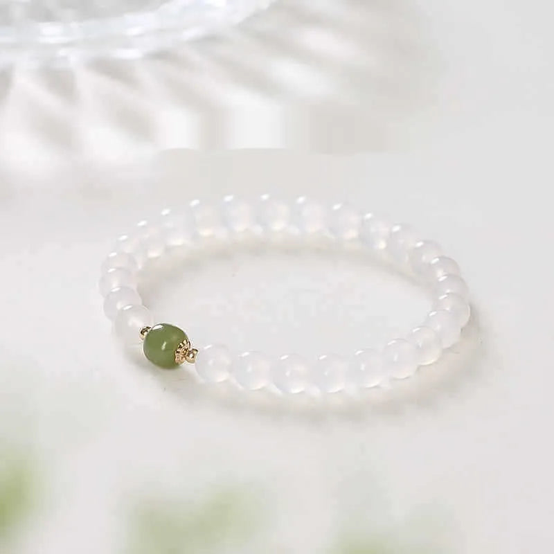 Handmade white agate crystal bracelet with cinnabar details on a wrist, showing 8mm bead size.