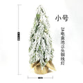 Small 24-inch plastic Christmas tree with LED lights and snow-covered branches on desktop