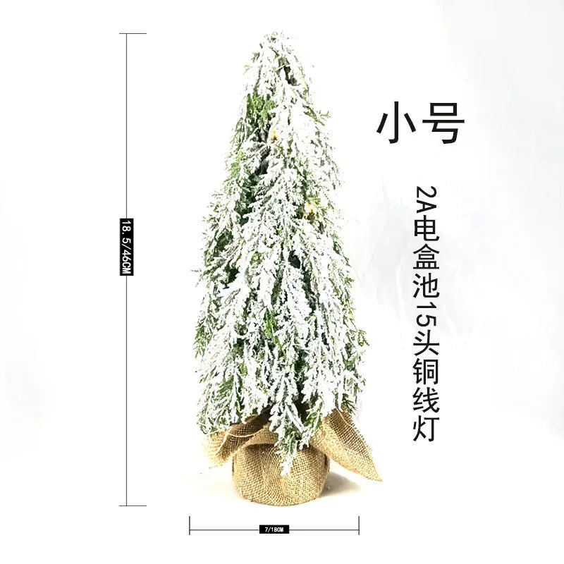 Small 24-inch plastic Christmas tree with LED lights and snow-covered branches on desktop