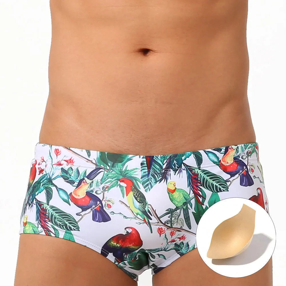 Men's blue swimming trunks with a detailed floral and bird print pattern, small boxer style