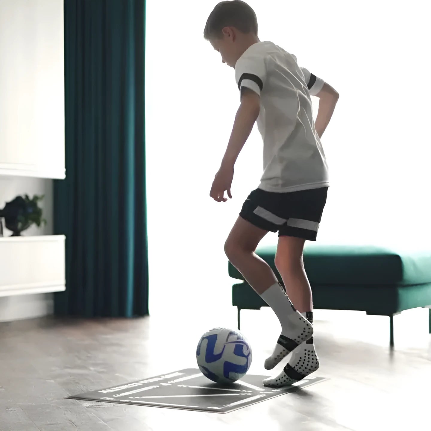 Black rubber football training mat measuring 60cm by 90cm on grass surface