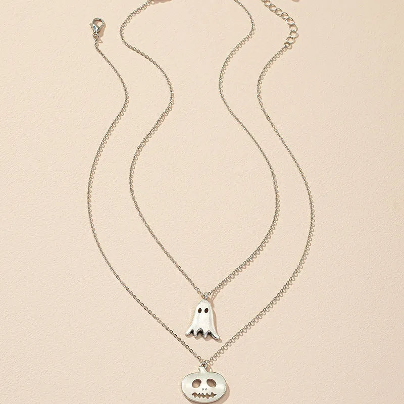 Two silver alloy pendant necklaces: one cartoon pumpkin and one cartoon ghost on a light background