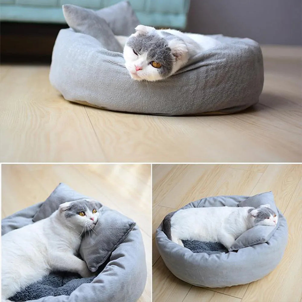 Grey round plush pet bed with raised edge and pillow, shown on a non-slip base.