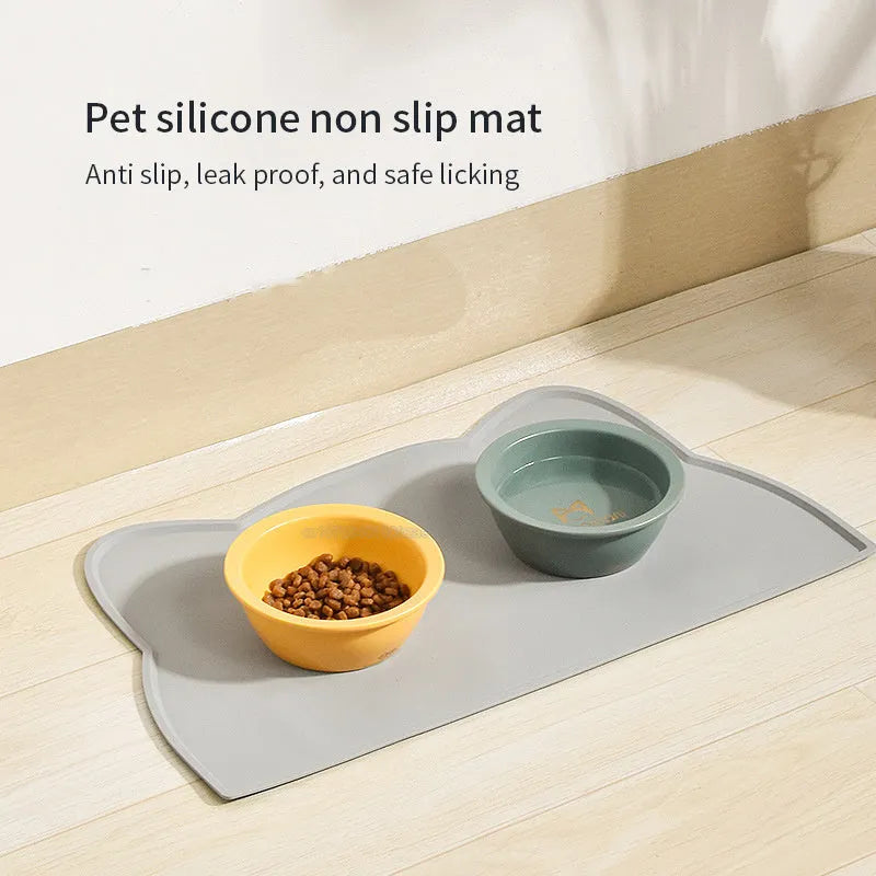 Blue silicone cat head-shaped pet feeding mat on a wooden floor