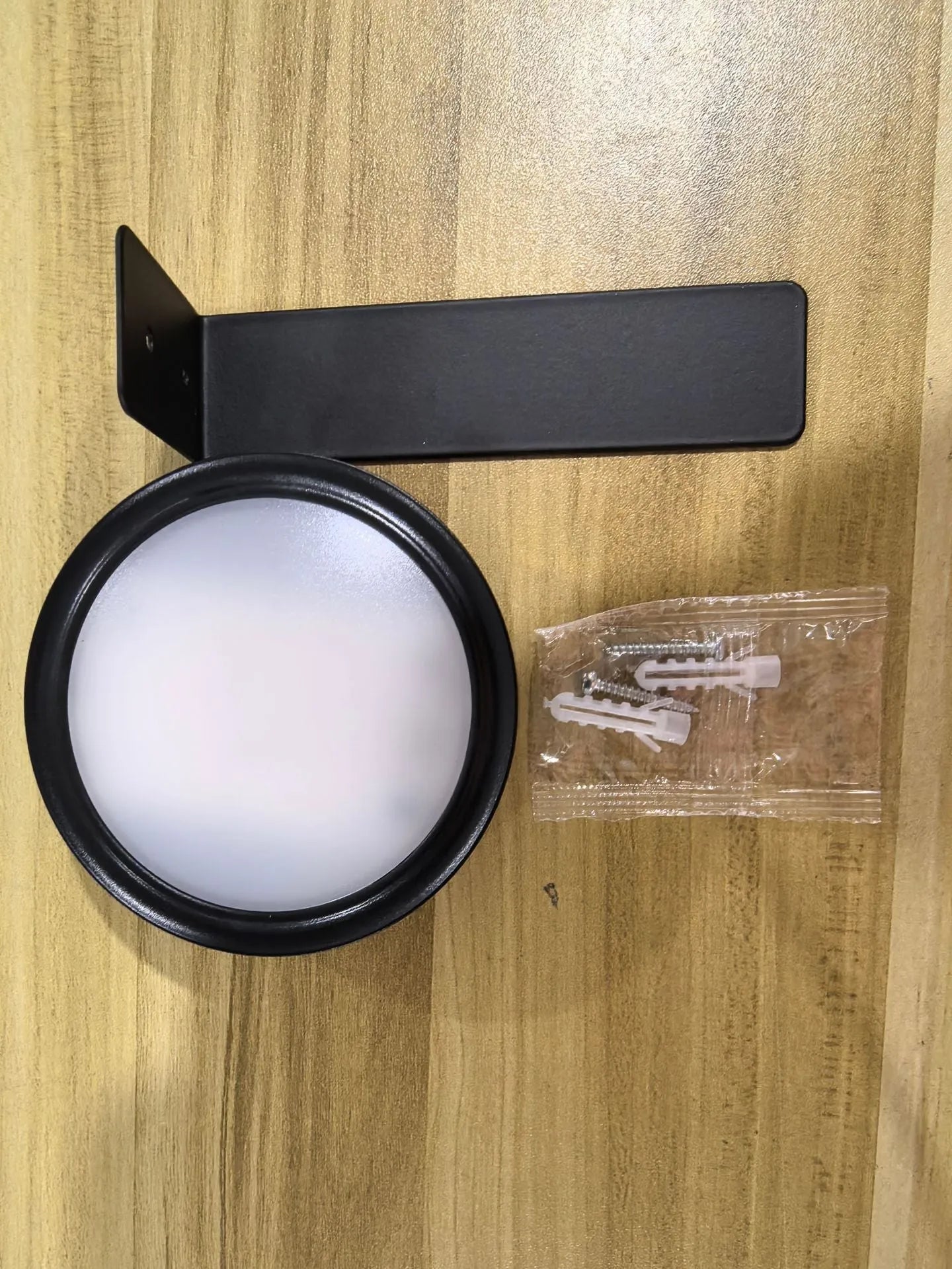 Black magnetic wireless LED lamp with remote control mounted next to a painting on a wall.