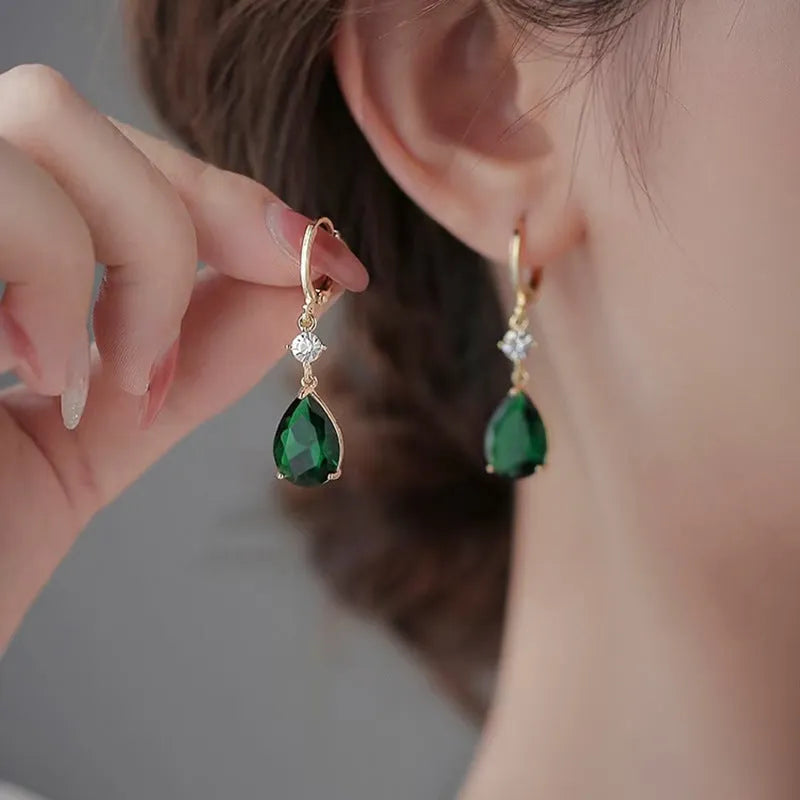 A pair of emerald green geometric teardrop alloy earrings on a plain background.