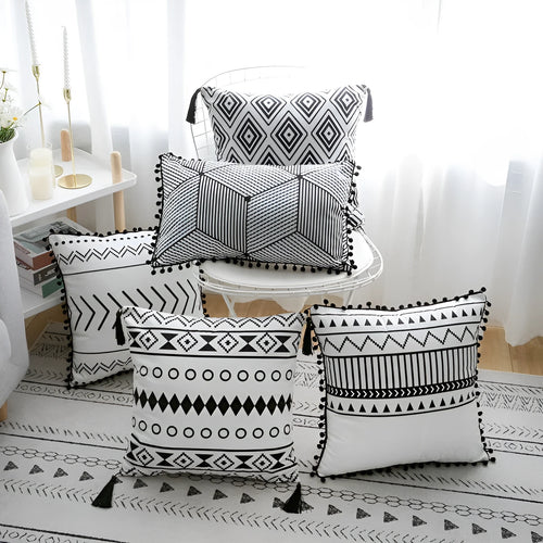 Bohemian style decorative throw pillow with polyester cover in light grey on a sofa.