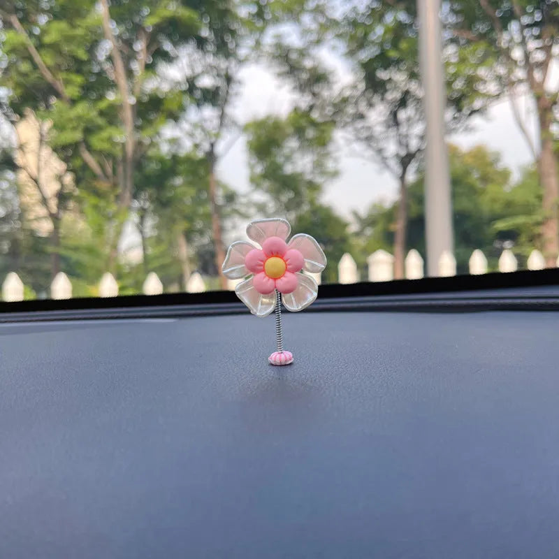 Small colourful plastic swing car decoration on a car dashboard, showing blue, green, pink, purple, and yellow colour options.