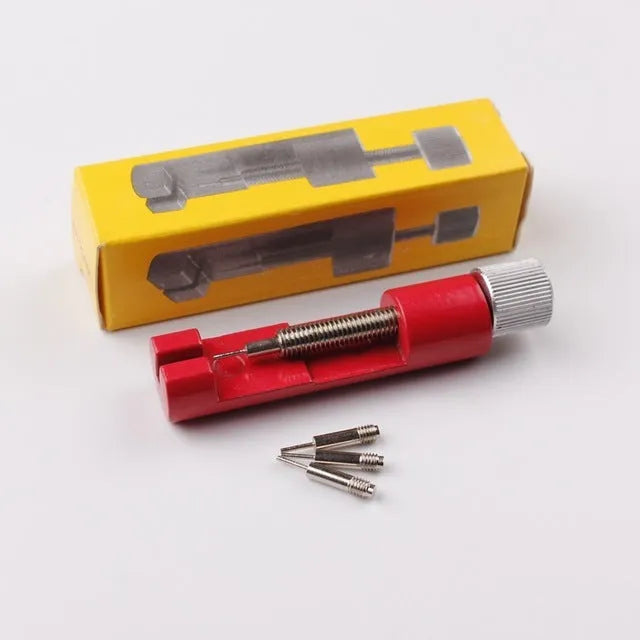Watch strap link remover tool in black with two thimbles and a metal watch band placed on the detacher groove