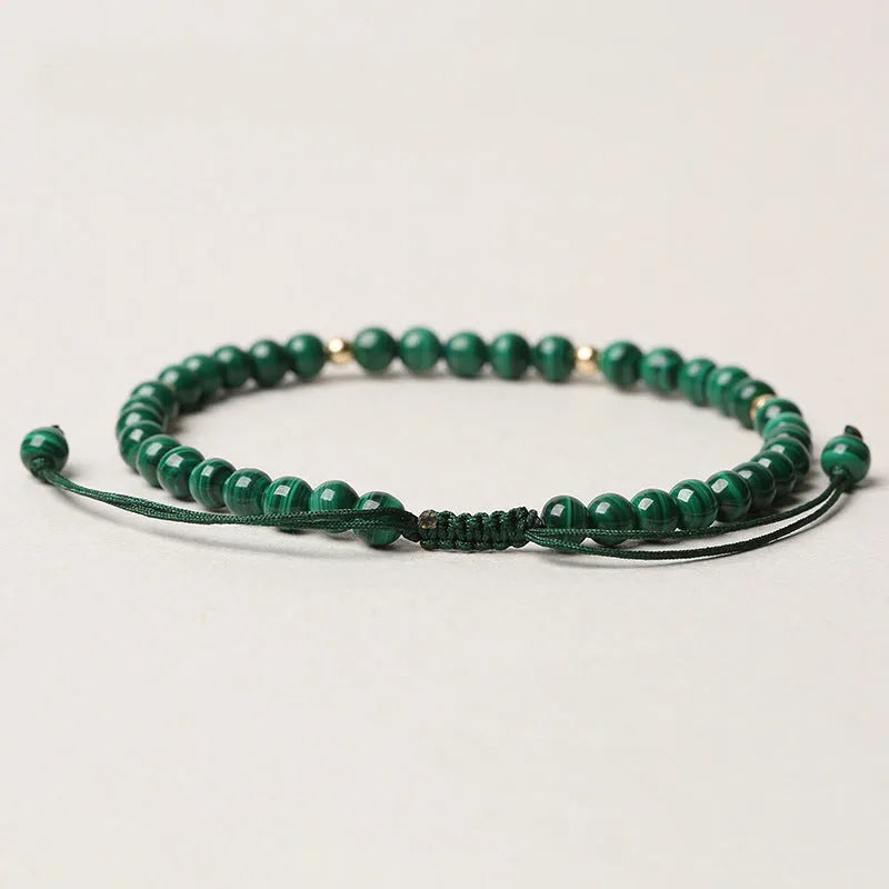 Natural green malachite crystal bracelet with golden balls on a woven hand strap.