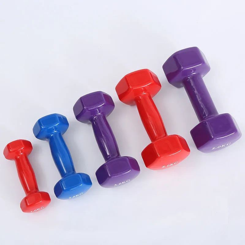 Set of bright coloured plastic fitness dumbbells in different weights on a floor.