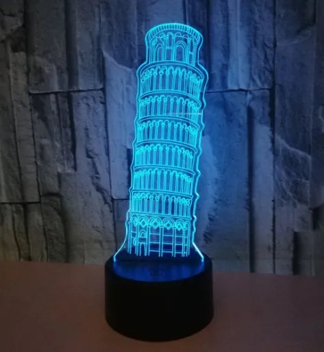 3D laser-cut Leaning Tower of Pisa nightlight glowing blue on a black base with a remote control.