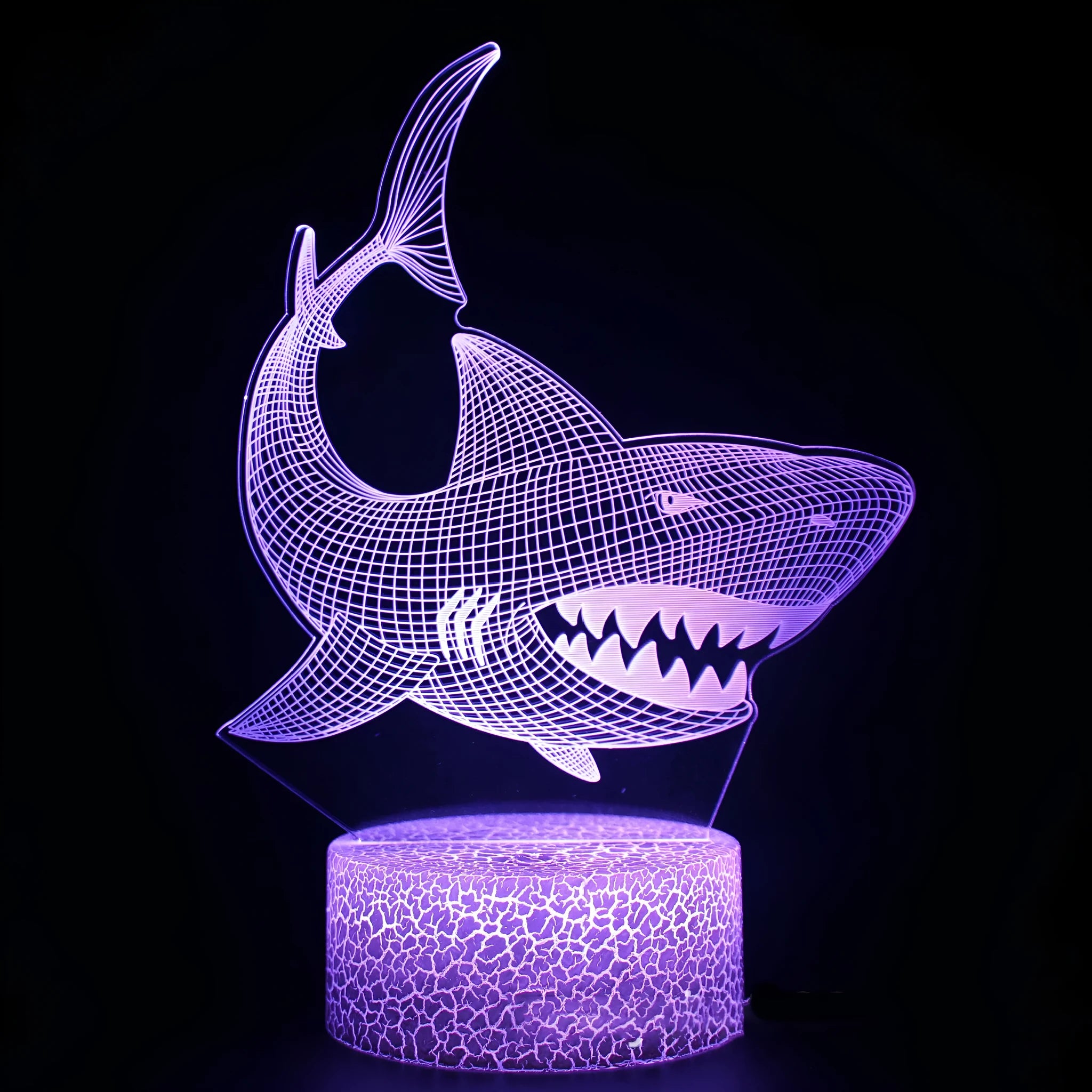 3D blue shark shaped LED table lamp with remote control on a wooden desk.