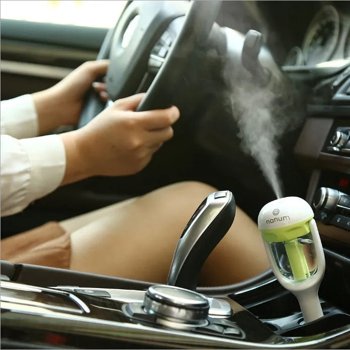 Compact blue portable car humidifier with essential oil diffuser on a car dashboard.