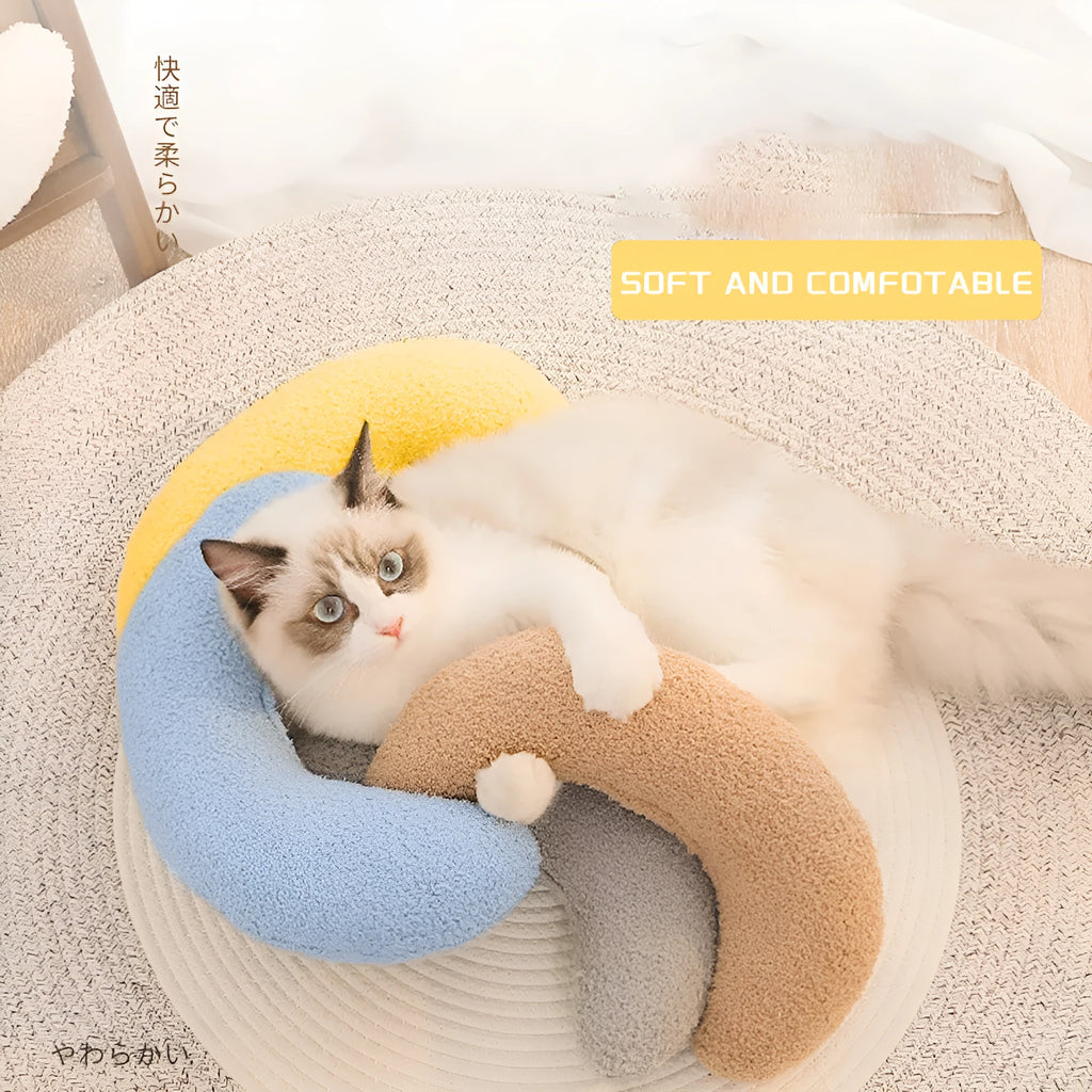Blue U-shaped cat pillow with adjustable fabric collar on a sofa
