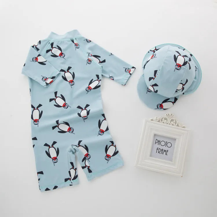 Boy in penguin print long sleeve one-piece swimsuit and matching swimming cap