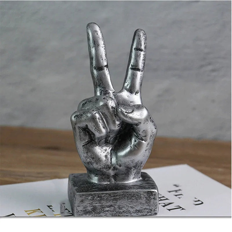 Resin hand gesture ornament in metallic finish on wooden surface