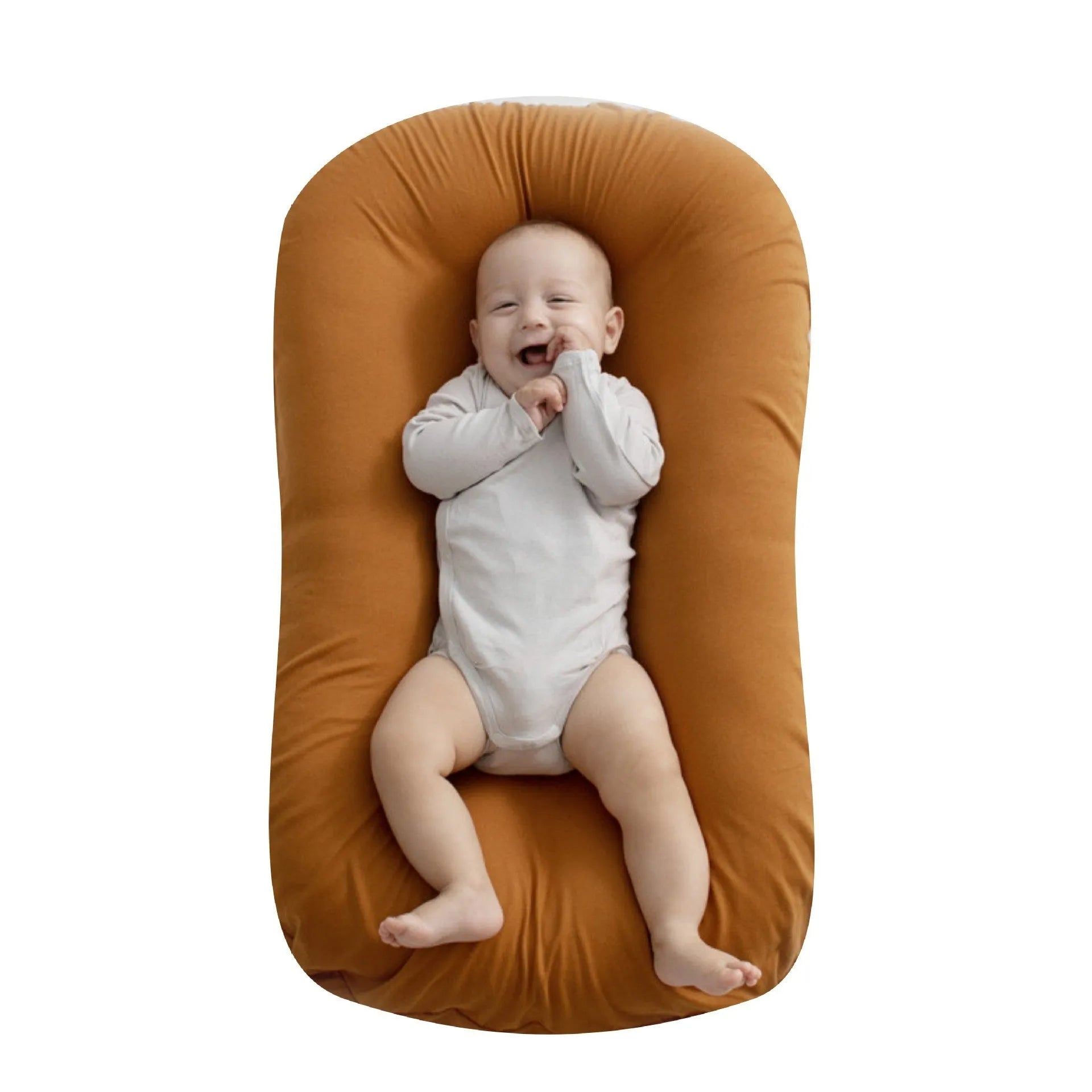 Beige portable baby nest cot crib for infants on a neutral background