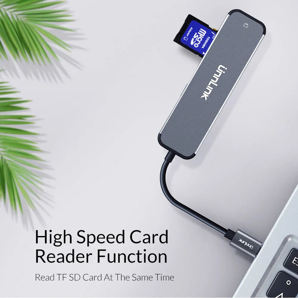Silver aluminium alloy type-C docking station with HDMI, SD/TF card reader, and USB 3.0 ports on a desk