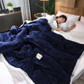 Thick coral fleece winter blanket in a solid colour, shown on a bed, dimensions 150cm by 200cm.