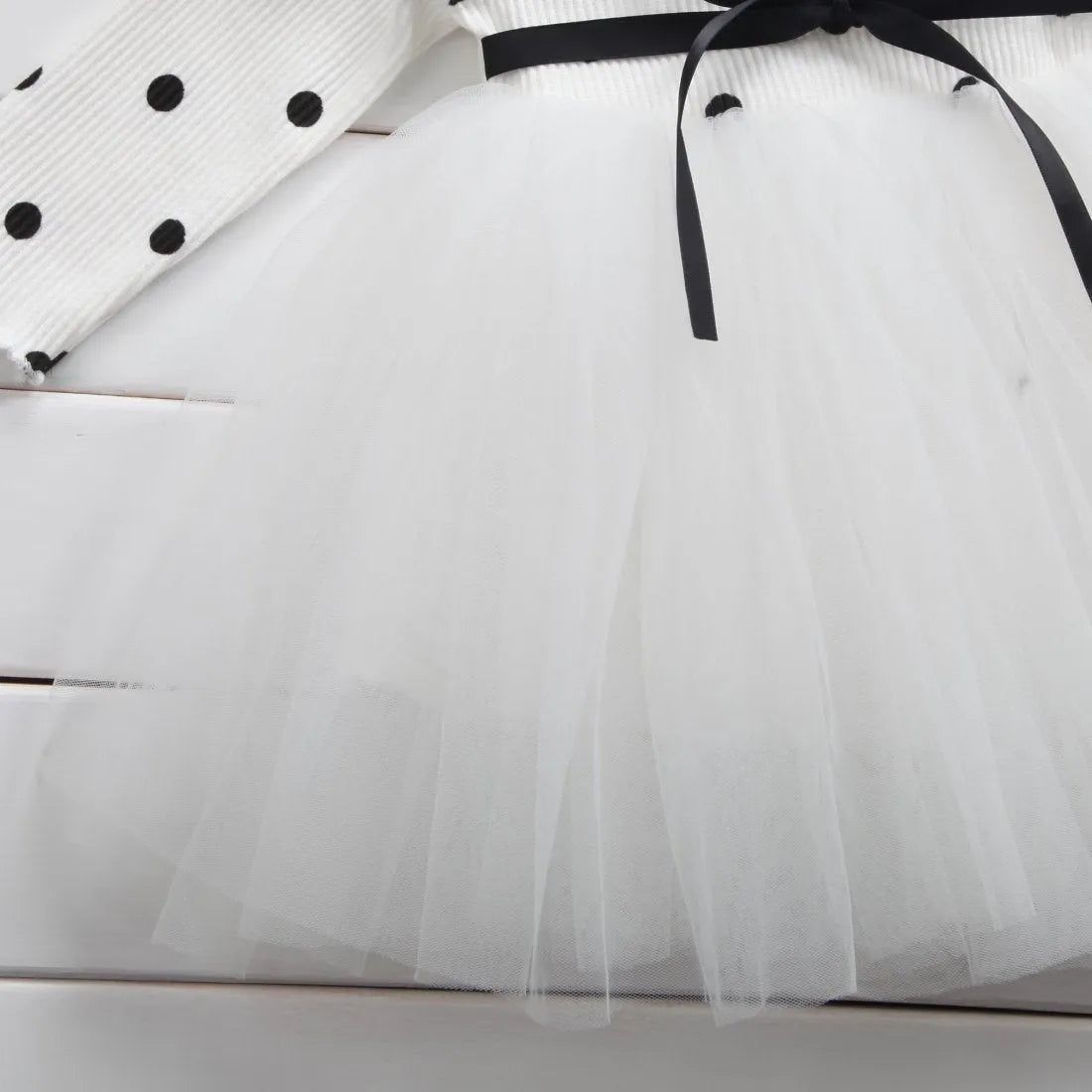 Baby girl wearing a long sleeve black tutu lace dress for a first birthday party.