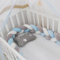 Close-up of a grey braid knot pillow cushion cot bumper fitted around white crib rails.
