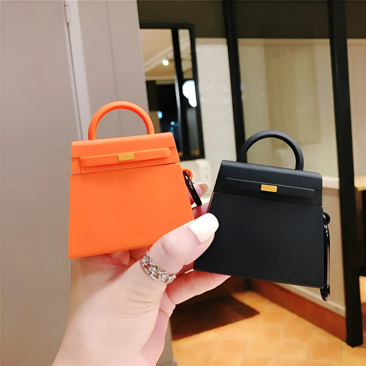 Silicone anti-drop earphone case for Apple AirPods 1 and 2 in black or orange, clamshell bag shape.