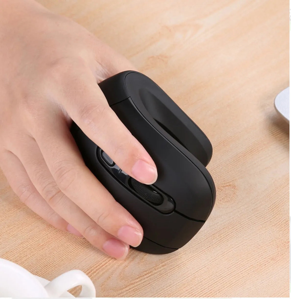 Wireless vertical mouse in black with ergonomic shape, six buttons, and diamond-pattern surface on a desk