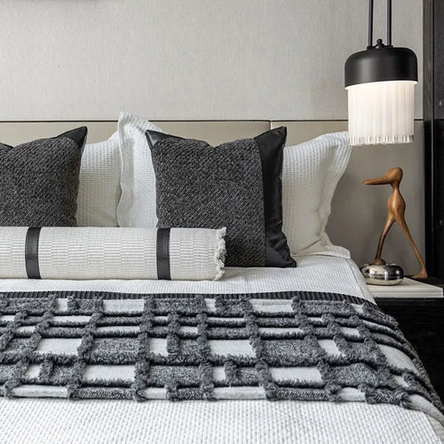 Grey and white plaid bed runner blanket set with a leather round pillow on a modern bed.