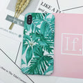 Green and pink painted hard PC back cover cases for smartphones on a table.