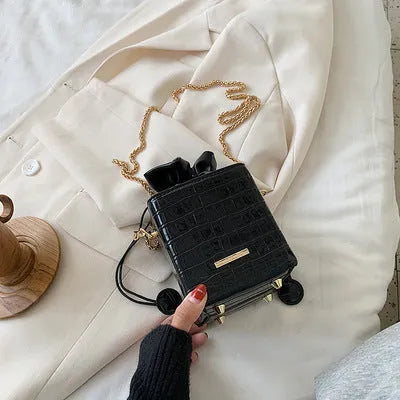 Small black bucket-shaped women's messenger bag with a drawstring top and metallic chain detail on the strap