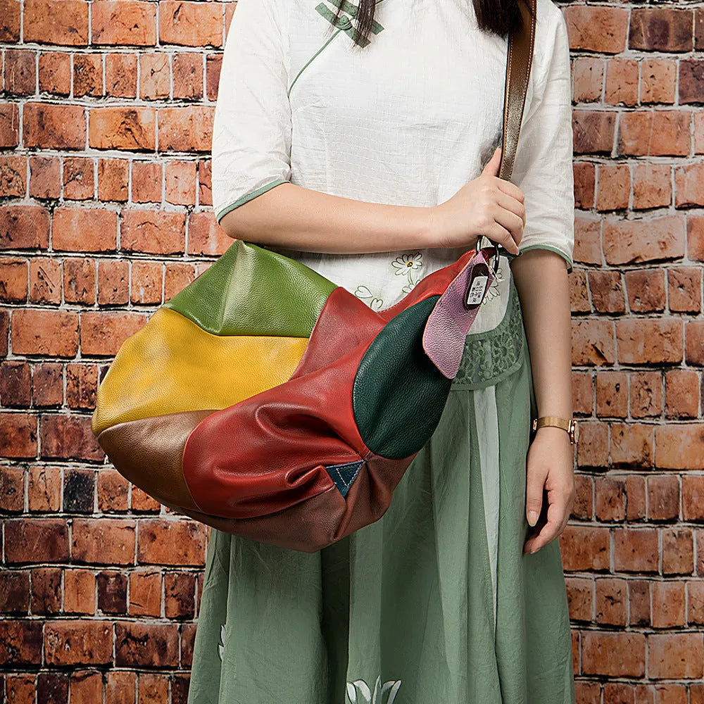 Brown cowhide leather crossbody travel bag with stitching detail, shown with laptop and A4 magazine.