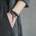 Men's ethnic black hair bracelet with white crystal tassel showing bending and lacing details