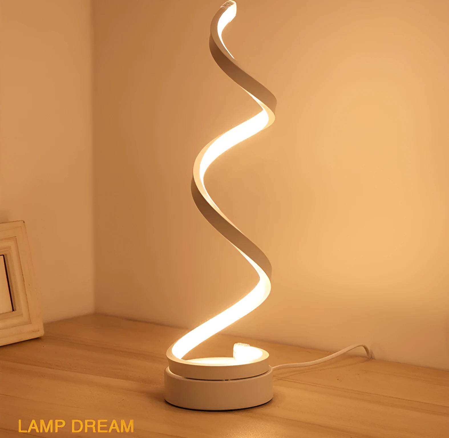 Modern LED table lamp with gold metal base and curved acrylic shade on a desk