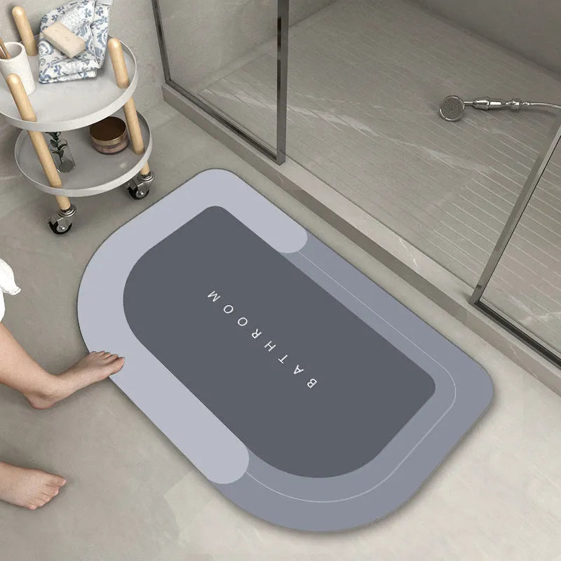 Machine-woven blended bathroom floor mat in blue, shown in an oval shape on a tiled floor.