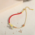 Gold-colour Koi fish charm bracelet in 925 silver with a red rope and peace buckle safety clasp.
