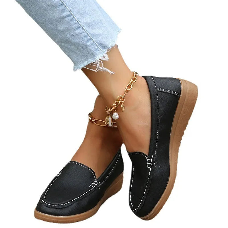 Women's black PU leather slip-on loafers with a round toe and flat rubber sole on a white background.
