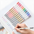 Set of twelve black Muji retractable gel pens with 0.5mm tips, laid out on a notepad.