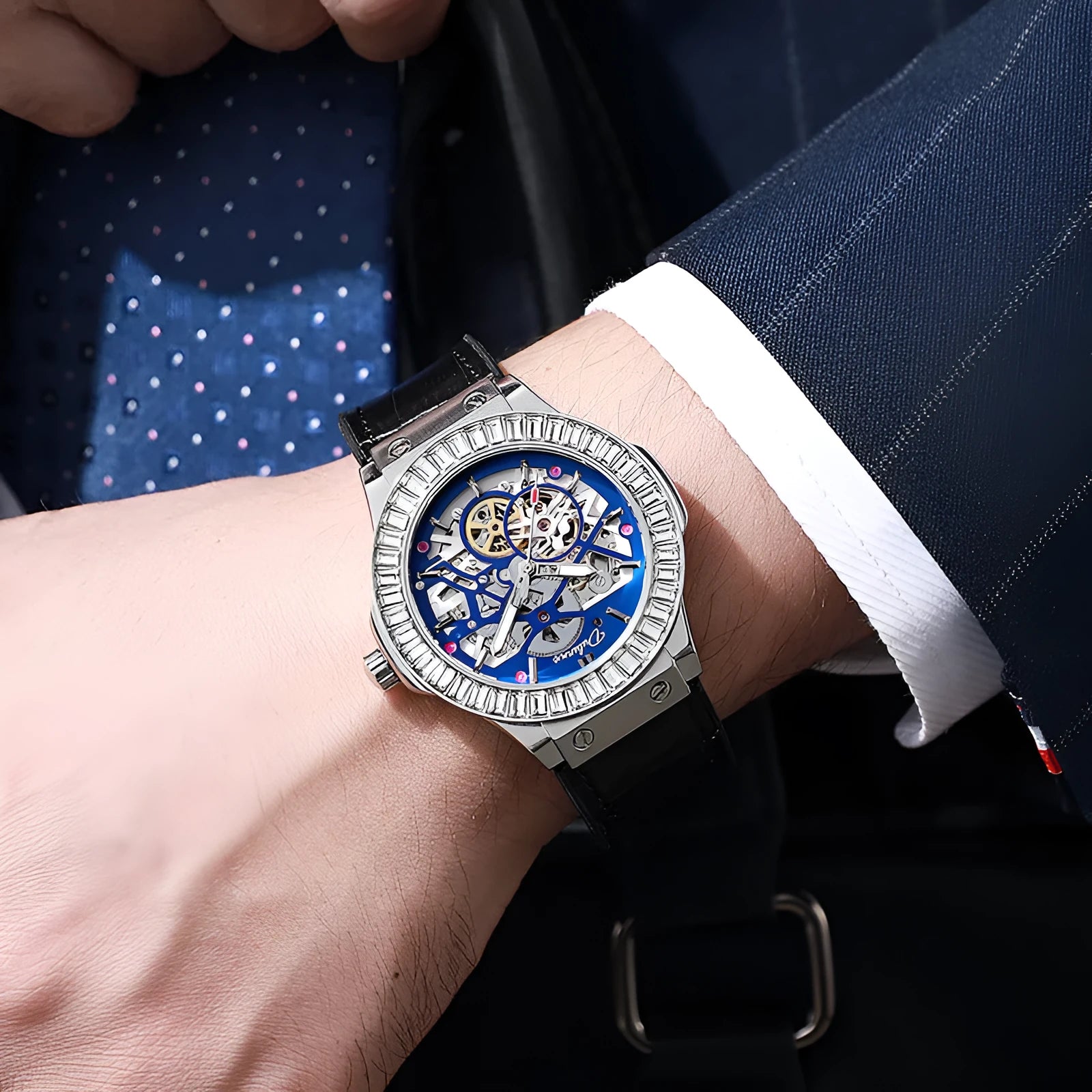 Men's automatic wristwatch with hollow dial showing mechanics, diamond studs on white case, on a black strap.
