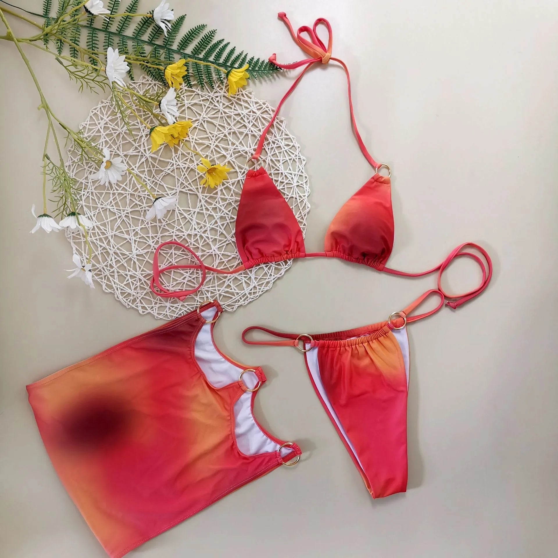 Tie-dye gradient pattern halter bikini top and briefs with matching skirt laid flat