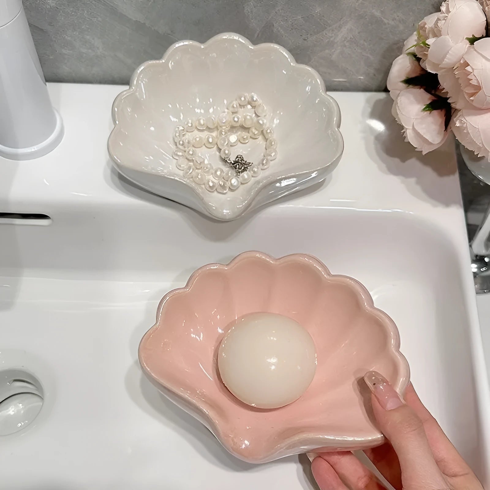 White or pink plastic shell-shaped soap dish for bathroom sink or shower.