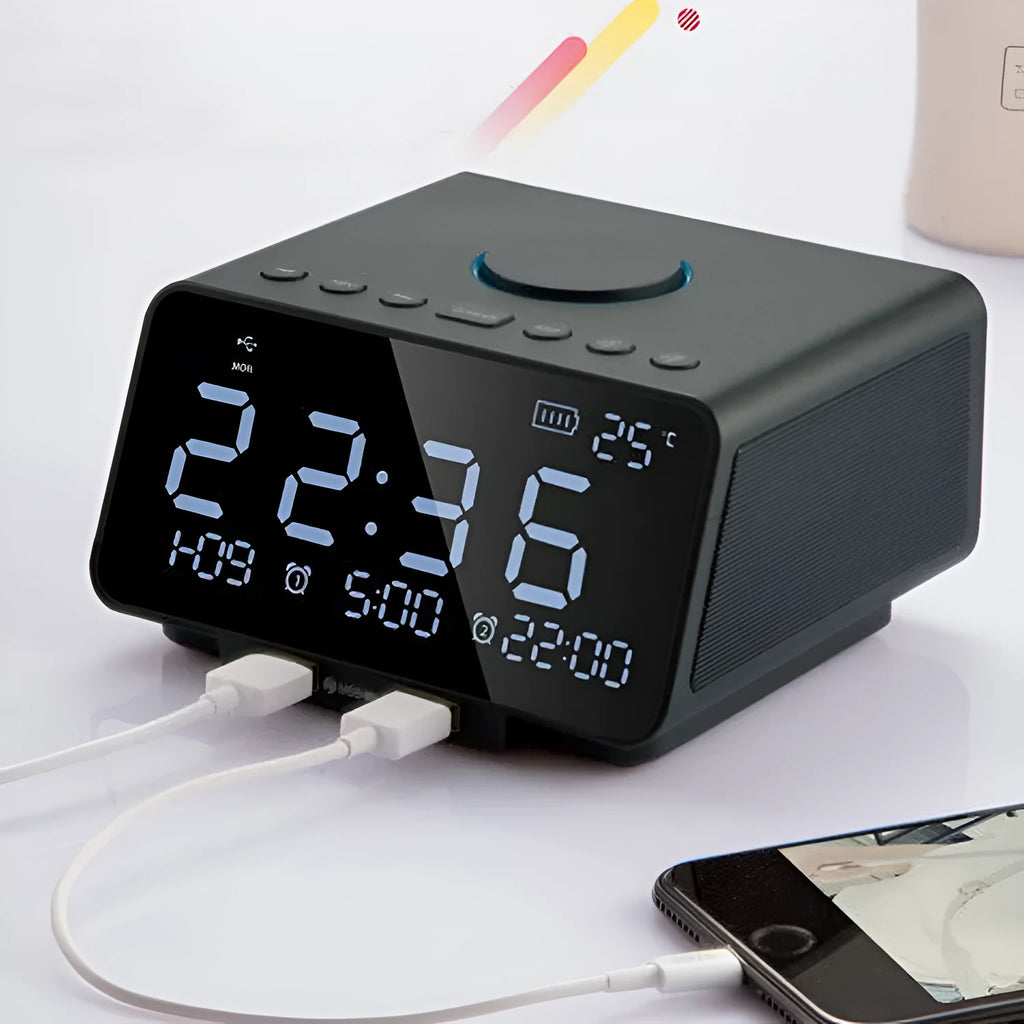 Black and white wireless alarm clock speaker with digital display, twin speakers, and a remote control on a wooden surface.