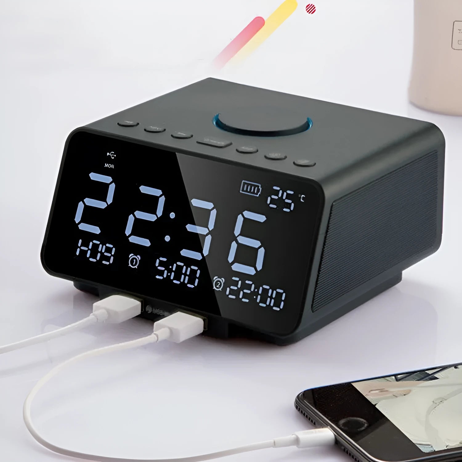 Black and white wireless alarm clock speaker with digital display, twin speakers, and a remote control on a wooden surface.