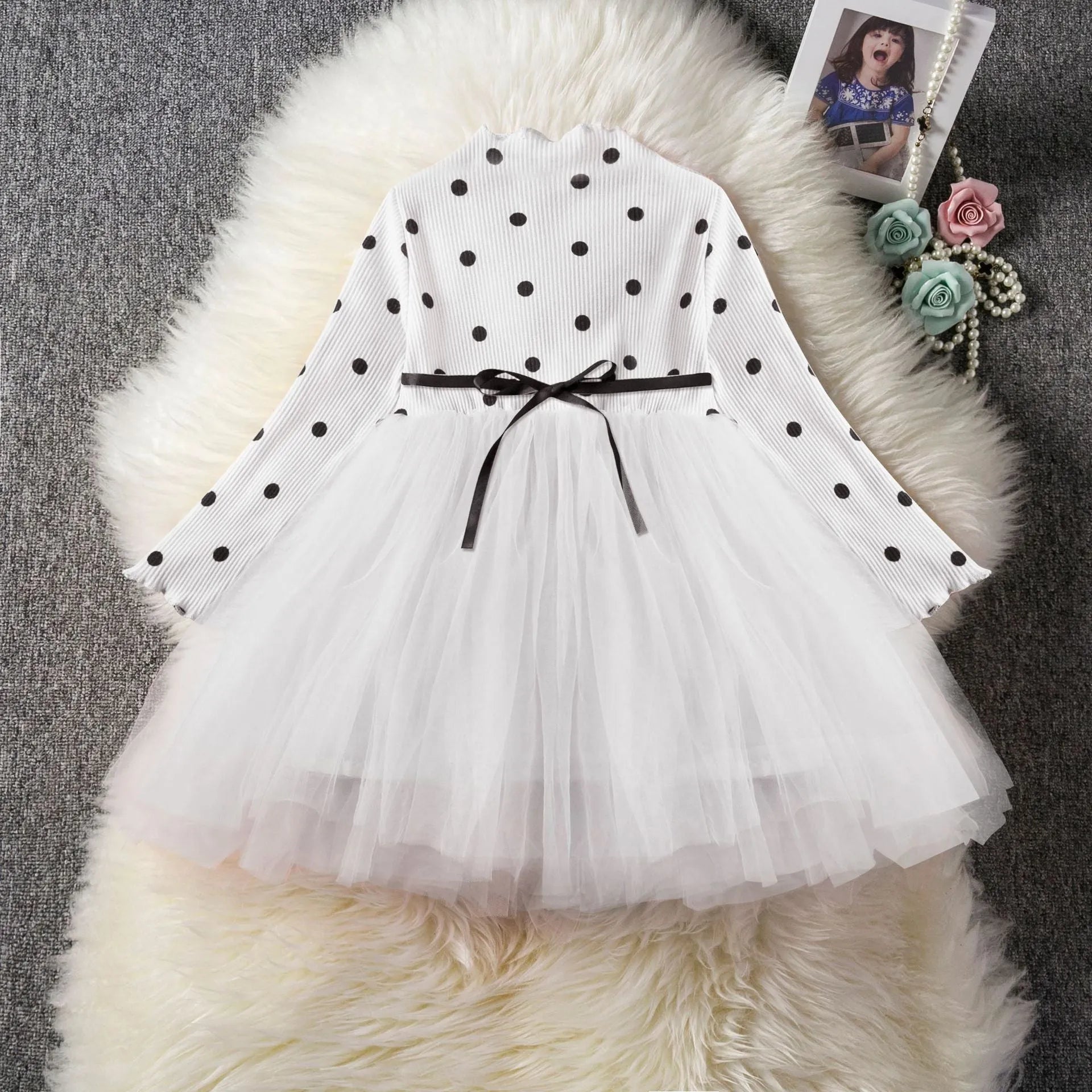 Baby girl wearing a long sleeve black tutu lace dress for a first birthday party.