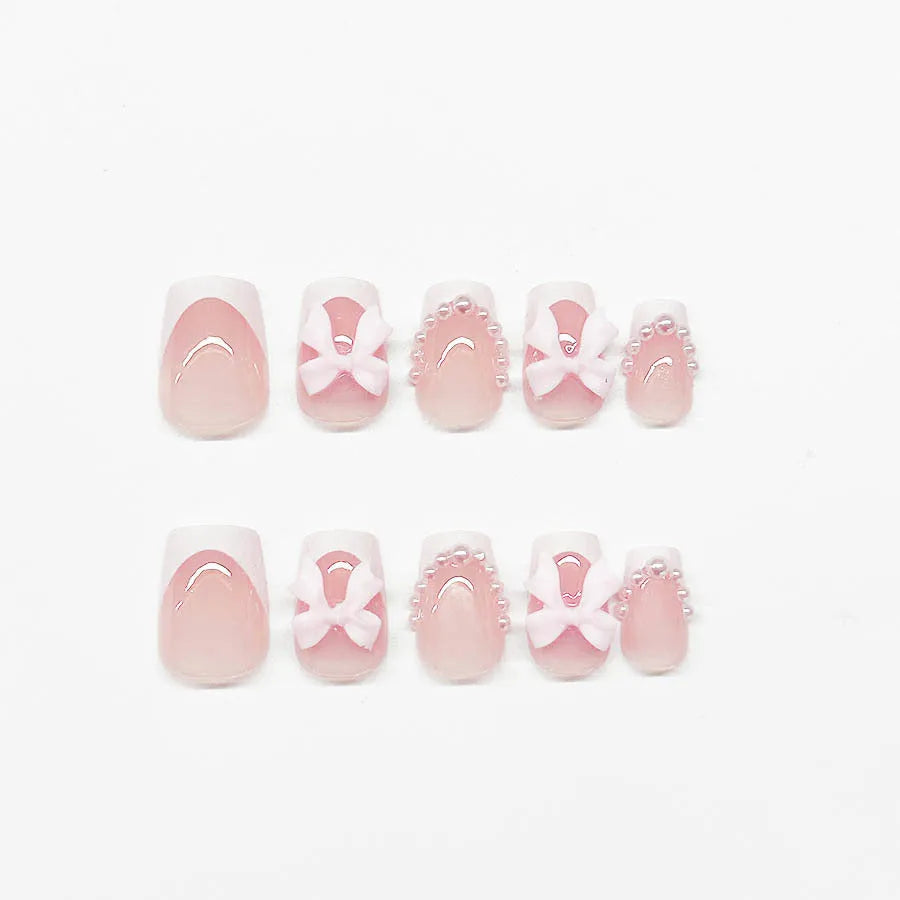 Short white French tip press-on nails with a cute pink bow design and a tulip pattern on a blush base.