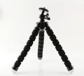 Black flexible octopus tripod with bent legs wrapped around a pole, showing a smartphone attached.
