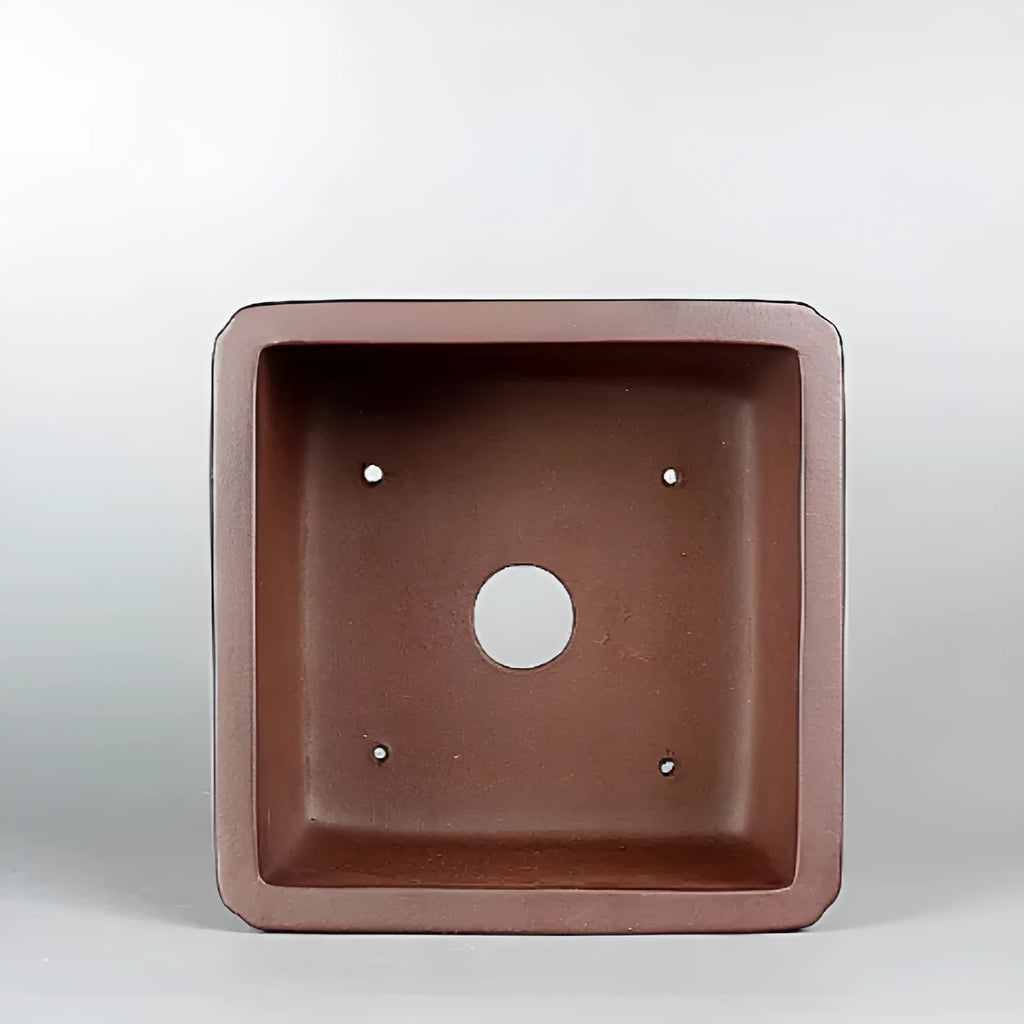 Brown handmade purple clay antique flower pot on a desktop.